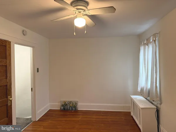 a view of empty room with window and wooden floor