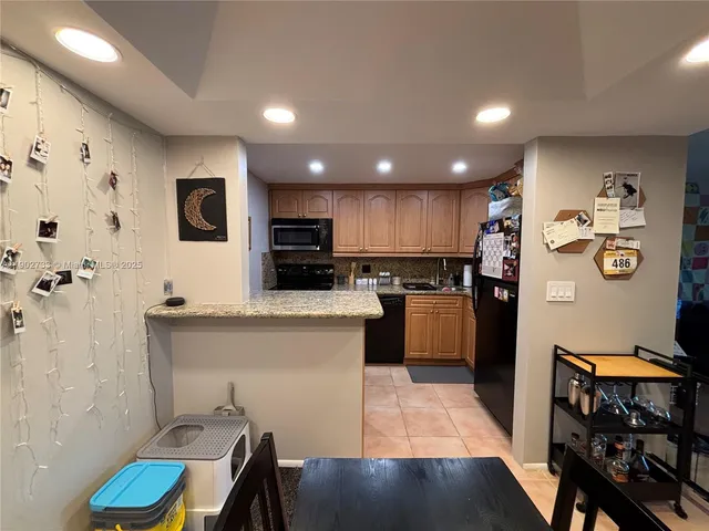 a kitchen with granite countertop a stove top oven microwave and refrigerator