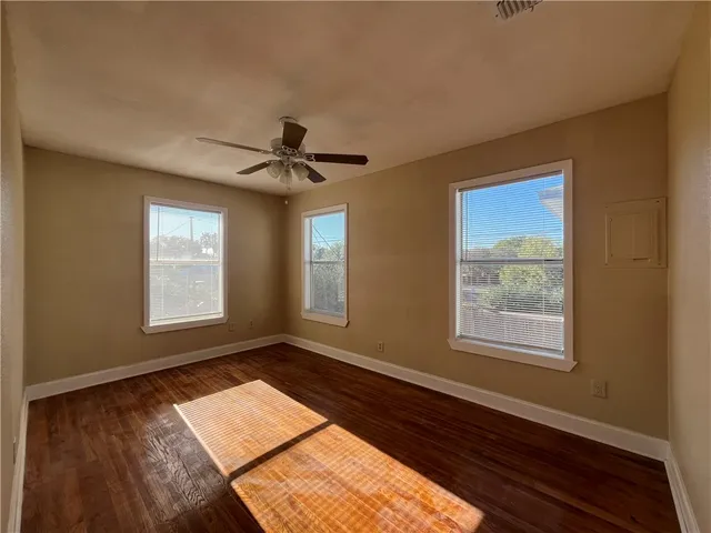 a view of an empty room with a window and wooden floor