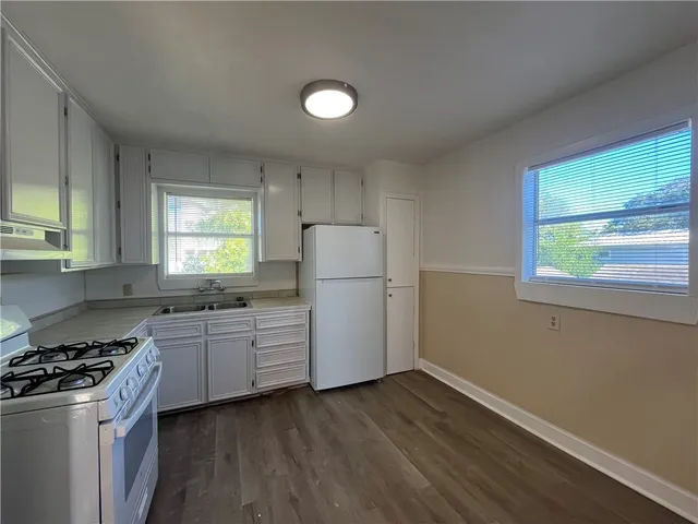 a kitchen with a sink a stove a refrigerator and white cabinets