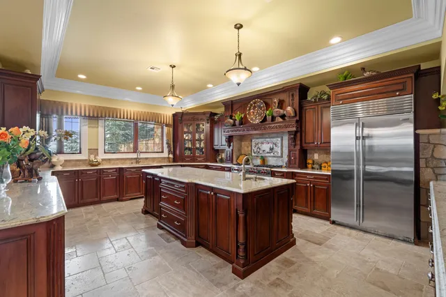 a kitchen with stainless steel appliances granite countertop a stove a sink a refrigerator and a wooden cabinets