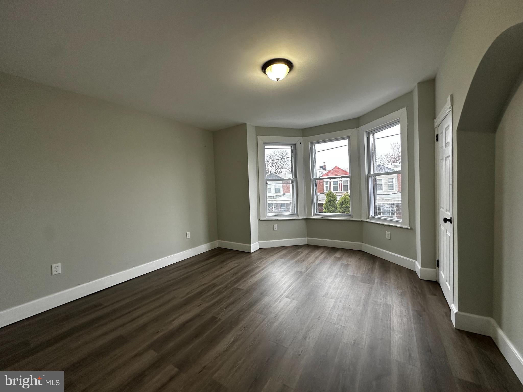 5729 Pine Street, Unit 2 Philadelphia, PA 19143 - Photo 12 of 21 an empty room with wooden floor and windows