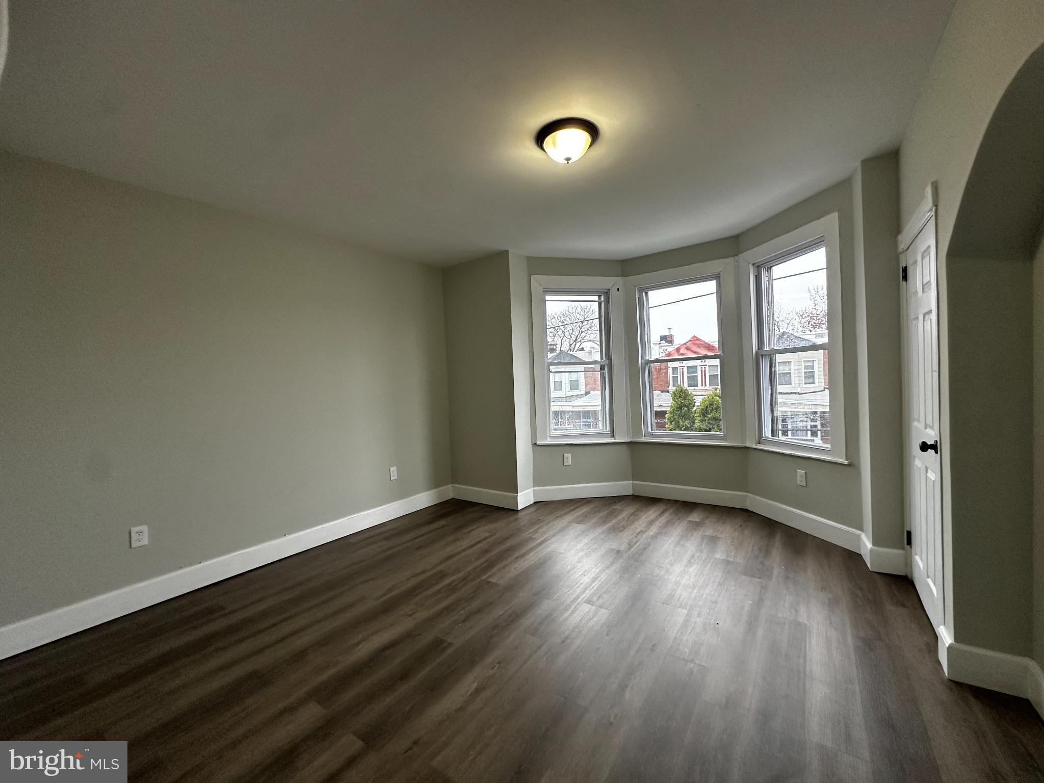 5729 Pine Street, Unit 2 Philadelphia, PA 19143 - Photo 13 of 21 an empty room with wooden floor and windows