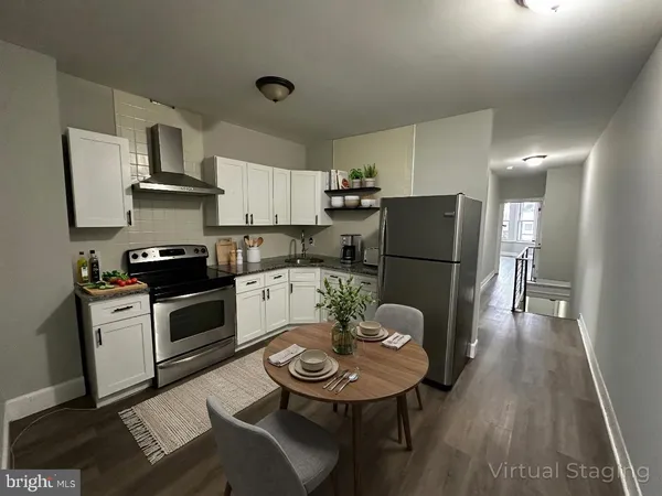 a kitchen with stainless steel appliances granite countertop a refrigerator a stove a sink a dining table and chairs