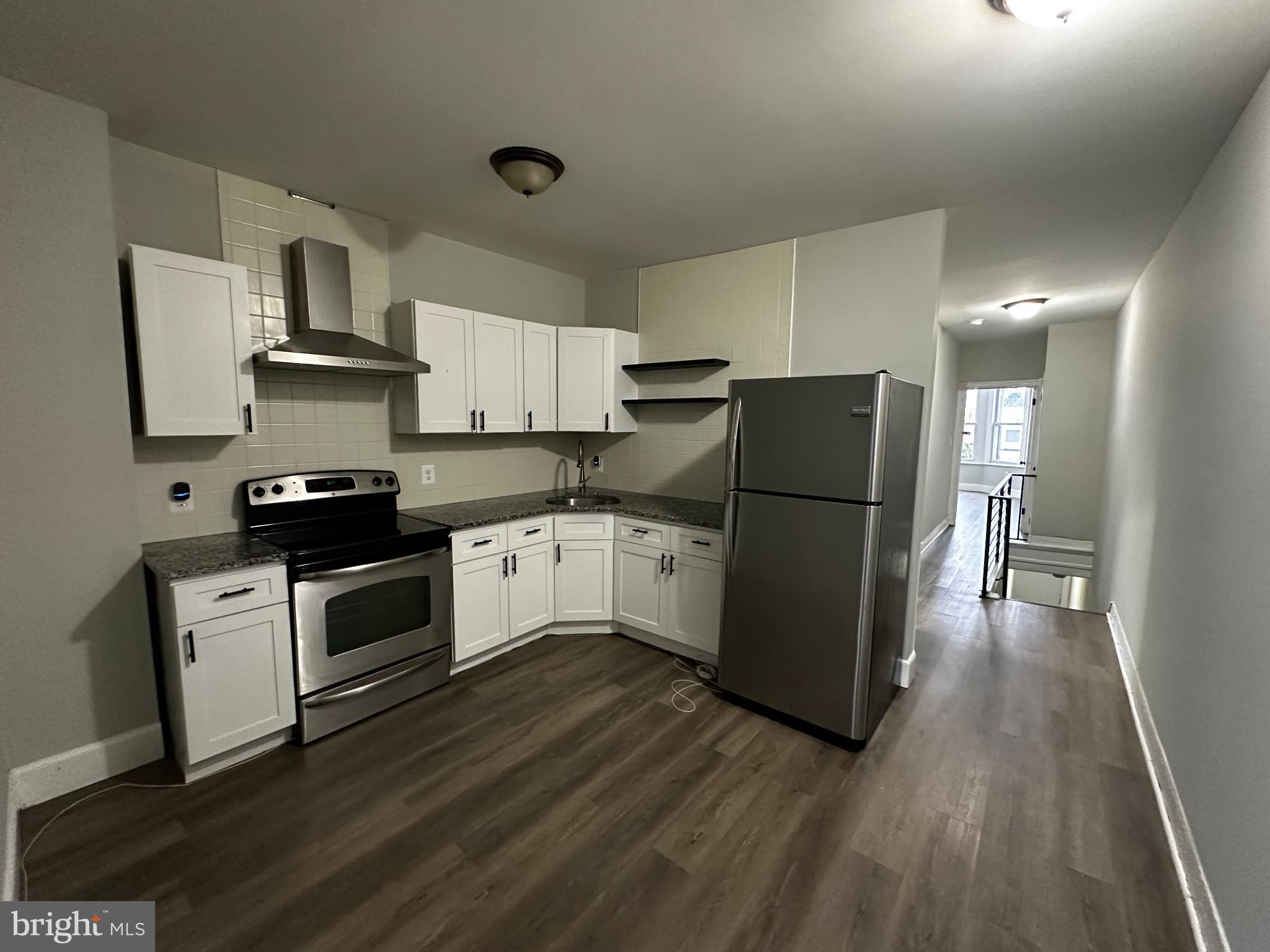 5729 Pine Street, Unit 2 Philadelphia, PA 19143 - Photo 6 of 21 a kitchen with a refrigerator a stove top oven and a counter space