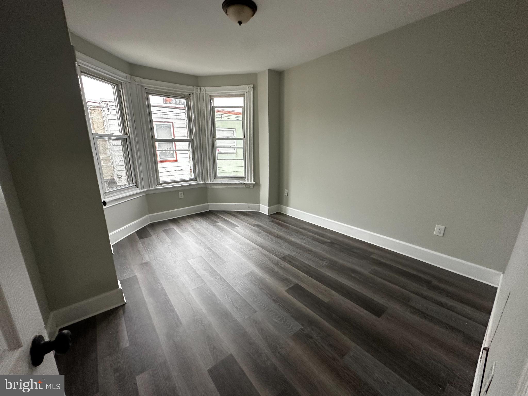 5729 Pine Street, Unit 2 Philadelphia, PA 19143 - Photo 7 of 21 an empty room with wooden floor and windows