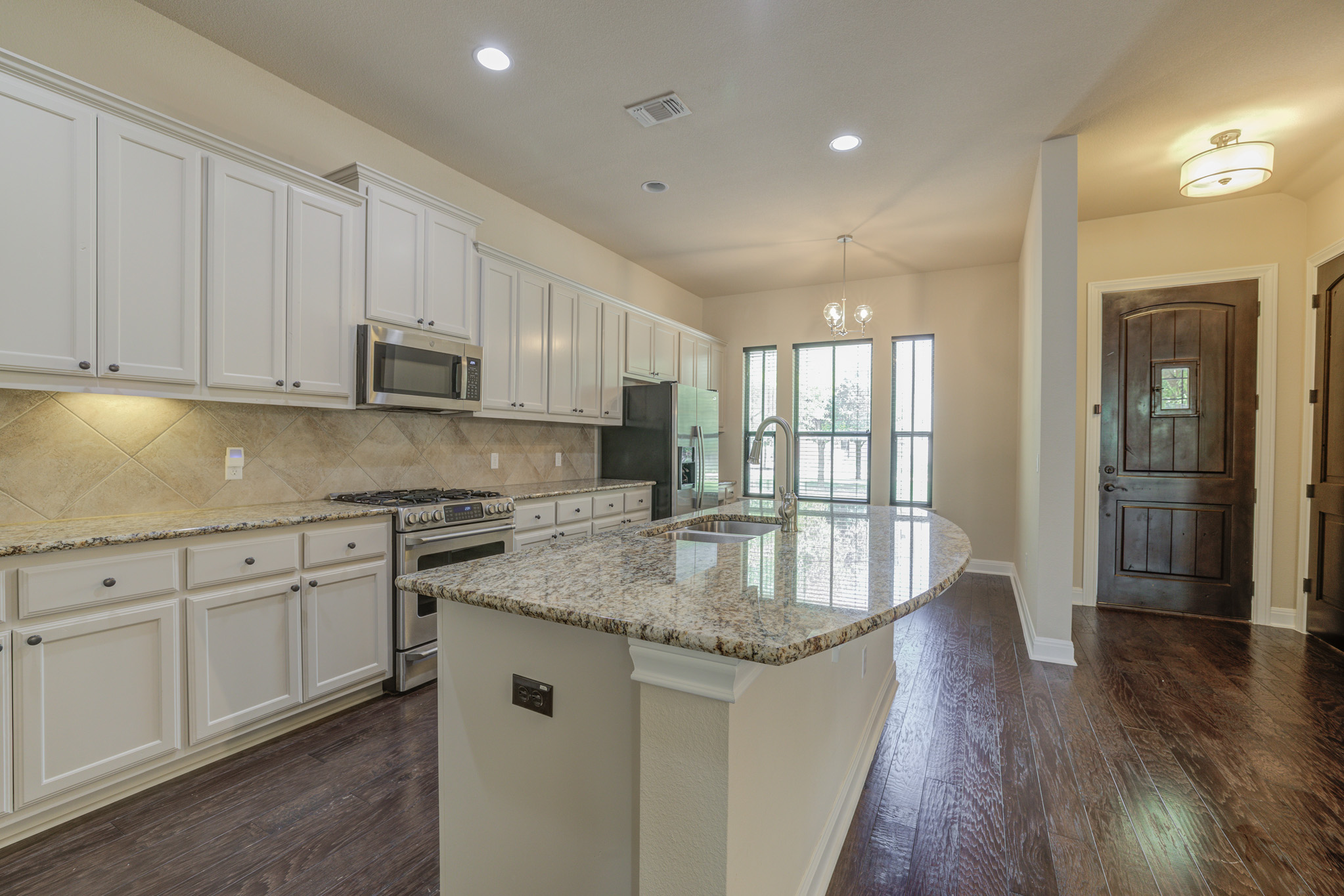 4524 Berkman Drive Austin, TX 78723 - Photo 8 of 38 Kitchen featuring light-toned cabinetry, granite countertops, stainless steel appliances, and a tiled backsplash