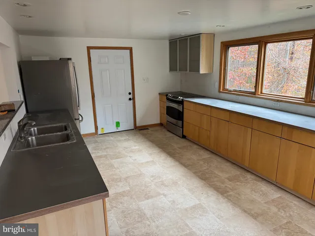a kitchen with granite countertop a stove a sink and a refrigerator