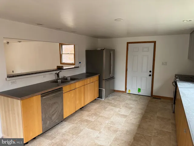 a large kitchen with a sink and dishwasher a refrigerator with wooden cabinets