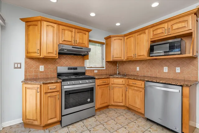 a kitchen with stainless steel appliances granite countertop a stove a sink and a microwave