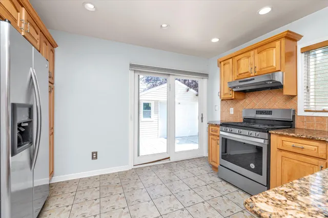 a kitchen with granite countertop a stove a sink and a refrigerator