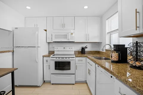 a kitchen with granite countertop white cabinets and white appliances