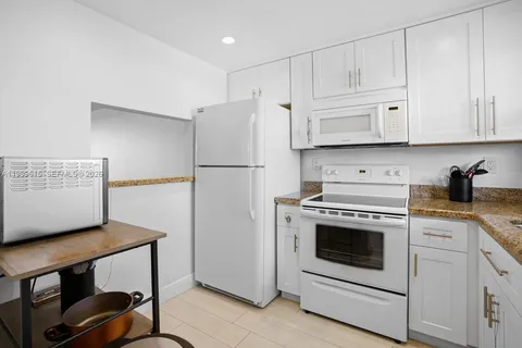 a kitchen with white cabinets and white appliances