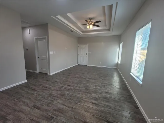 an empty room with wooden floor mirror and windows