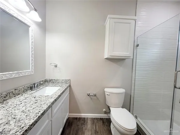 a bathroom with a granite countertop toilet and a sink