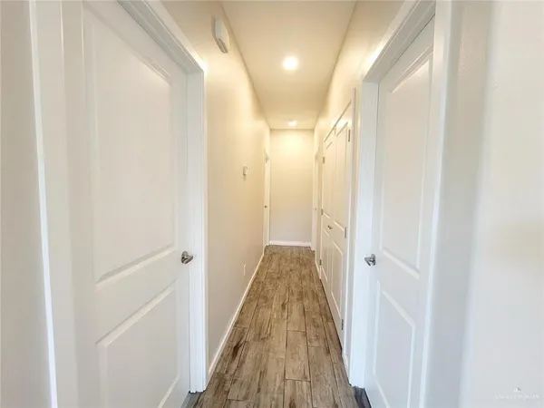 a view of a hallway with wooden floor and a glass door