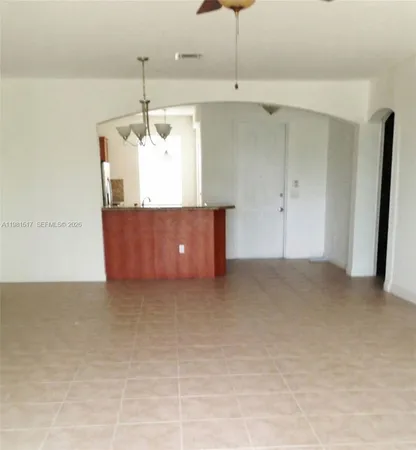 a living room with stainless steel appliances kitchen island granite countertop a refrigerator a stove and a sink