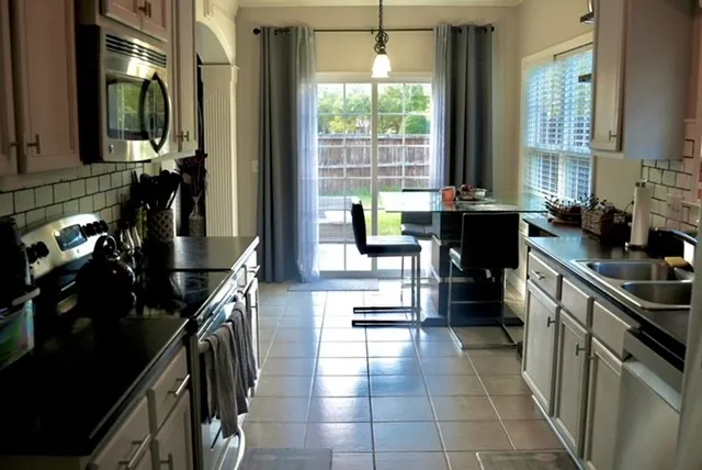 a kitchen with granite countertop a stove a sink and a refrigerator