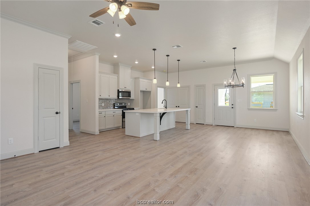 a view of a kitchen with a kitchen island wooden floor appliances and a chandelier