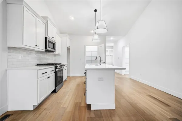 a large kitchen with cabinets wooden floor and stainless steel appliances