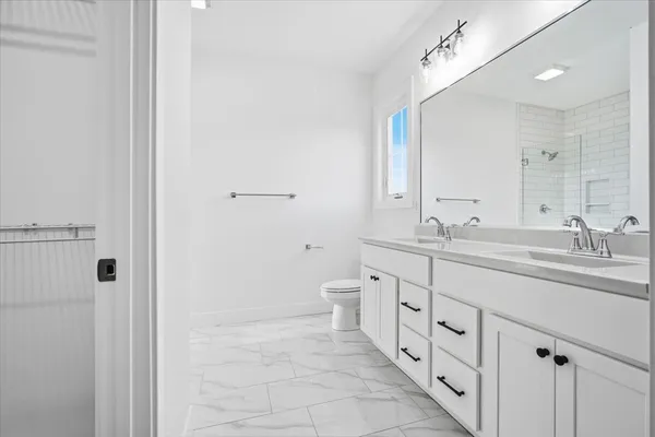 a spacious bathroom with a double vanity sink a toilet and a shower