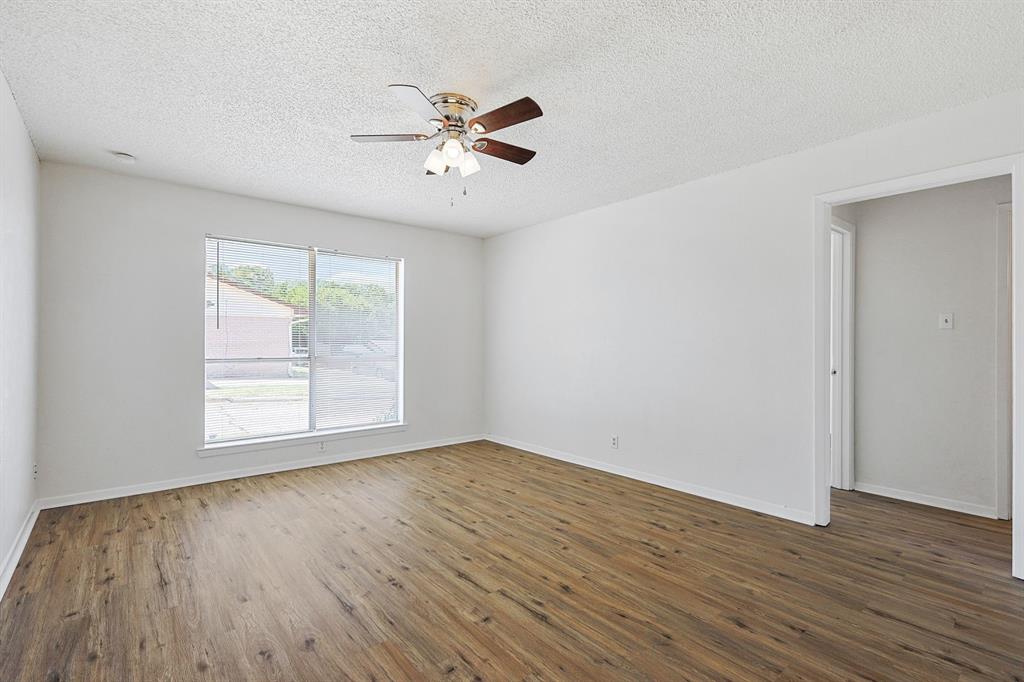 2637 West Randol Mill Road, Unit 2639D Arlington, TX 76012 - Photo 9 of 15 Spacious room featuring wood-finish flooring, white walls, and a large window with blinds