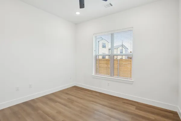 an empty room with wooden floor and ceiling fan