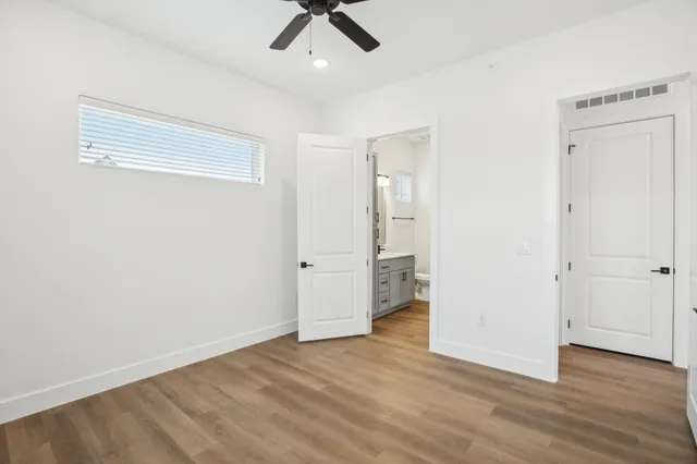 an empty room with wooden floor and ceiling fan