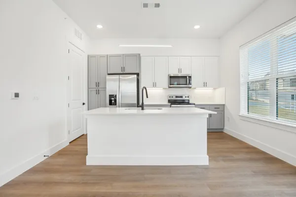 a kitchen with kitchen island a sink a stove a refrigerator and white cabinets