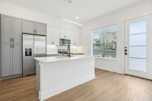 a kitchen with kitchen island a counter top space wooden floor and stainless steel appliances