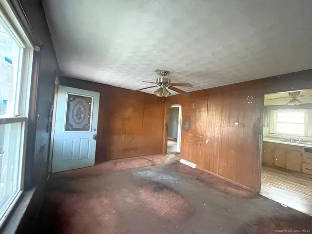 an empty room with windows and chandelier fan