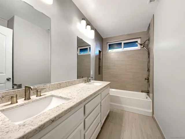a bathroom with a granite countertop sink a mirror and a bathtub