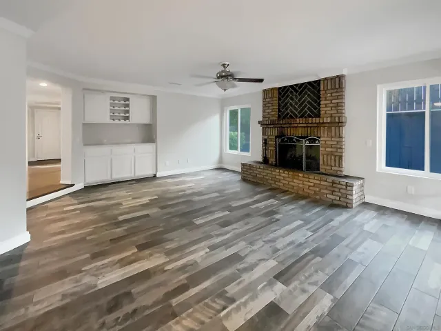 a view of a livingroom with a fireplace a chandelier and wooden floor