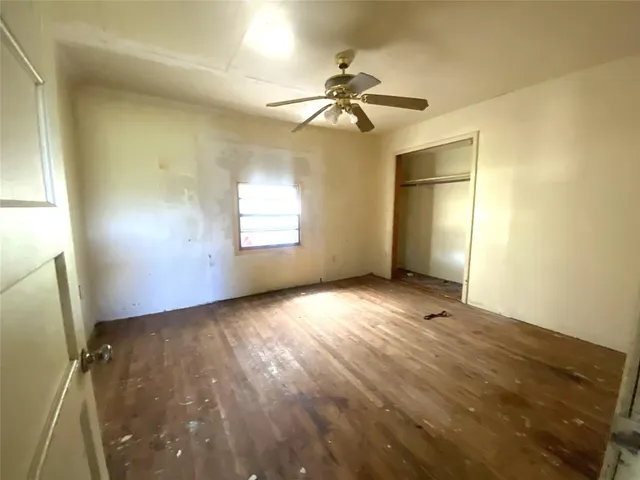 an empty room with windows and fan