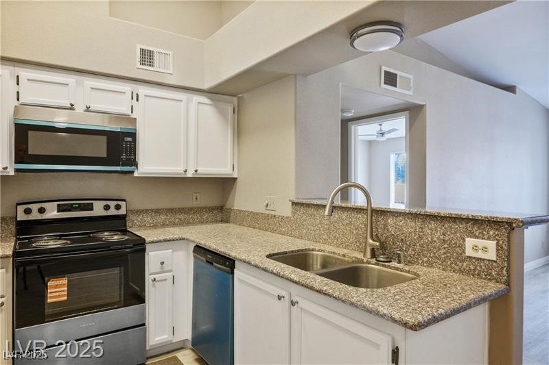 1575 West Warm Springs Road, Unit 2122 Henderson, NV 89014 - Photo 16 of 24 Kitchen with white cabinetry, appliances with stainless steel finishes, light stone countertops, a peninsula, and ceiling fan