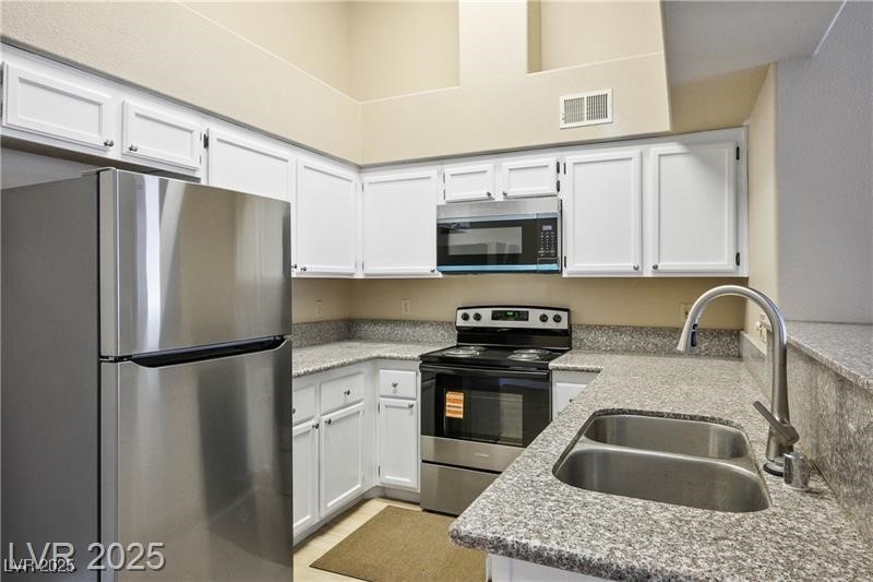1575 West Warm Springs Road, Unit 2122 Henderson, NV 89014 - Photo 9 of 24 Kitchen featuring stainless steel appliances, white cabinets, and light stone countertops