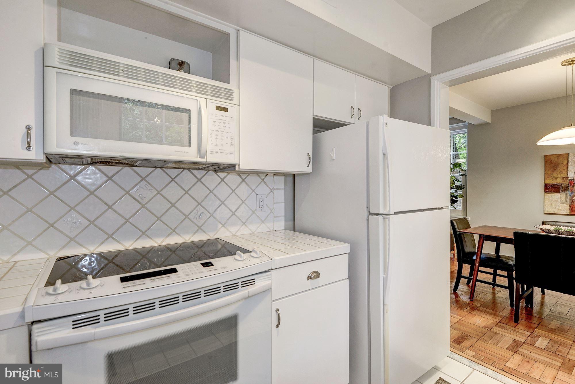 3500 39th Street Northwest, Unit B668 Washington, DC 20016 - Photo 13 of 29 a kitchen with a stove a refrigerator and a dining table