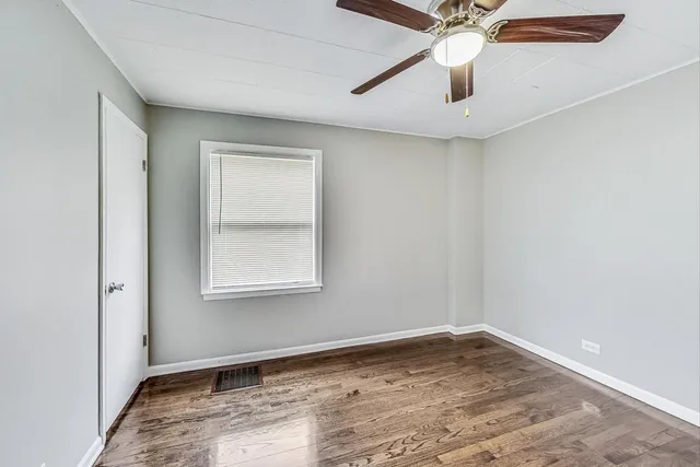 an empty room with a window and ceiling fan