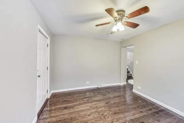 an empty room with a ceiling fan and wooden floor
