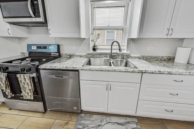 a kitchen with granite countertop a sink stove and cabinets