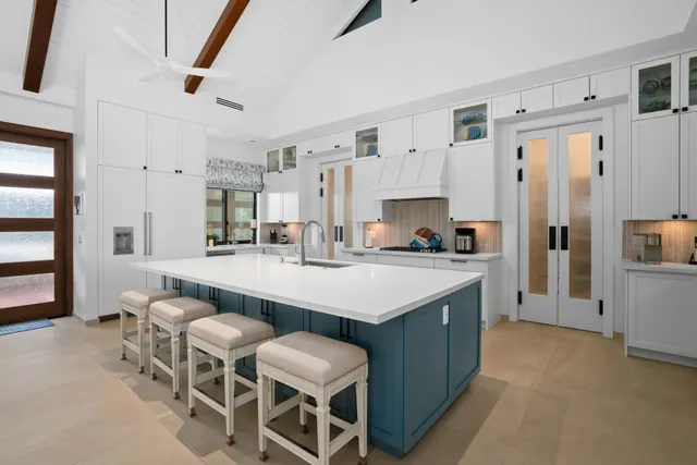a large kitchen with cabinets chairs and refrigerator