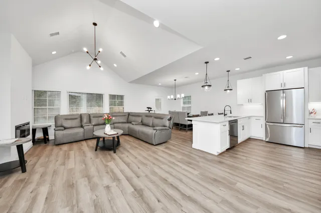 a living room with couches and kitchen view with wooden floor