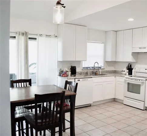 a kitchen with a dining table chairs and white appliances