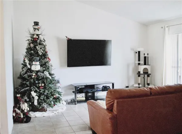 a living room with furniture a potted plant and a flat screen tv