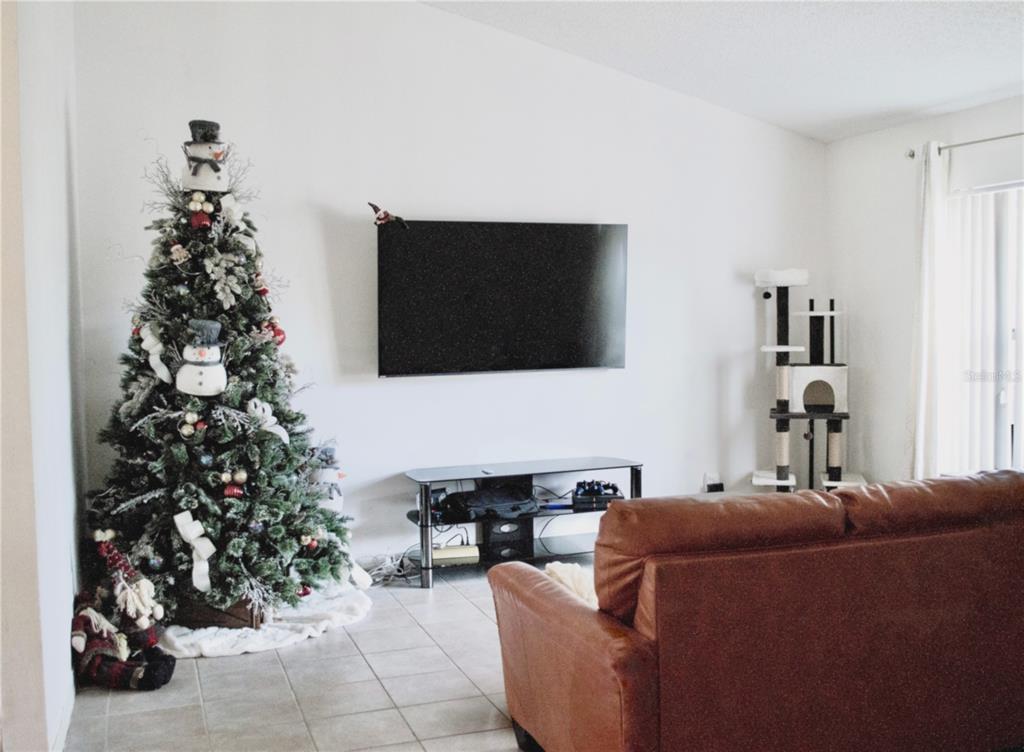 360 Cocoa Court Kissimmee, FL 34758 - Photo 4 of 11 a living room with furniture a potted plant and a flat screen tv