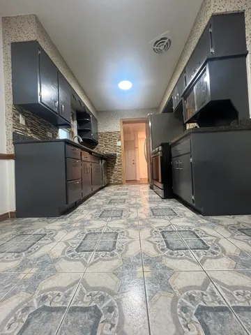 a kitchen with stainless steel appliances kitchen island granite countertop a refrigerator and a sink