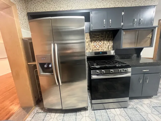a metallic refrigerator freezer sitting inside of a kitchen