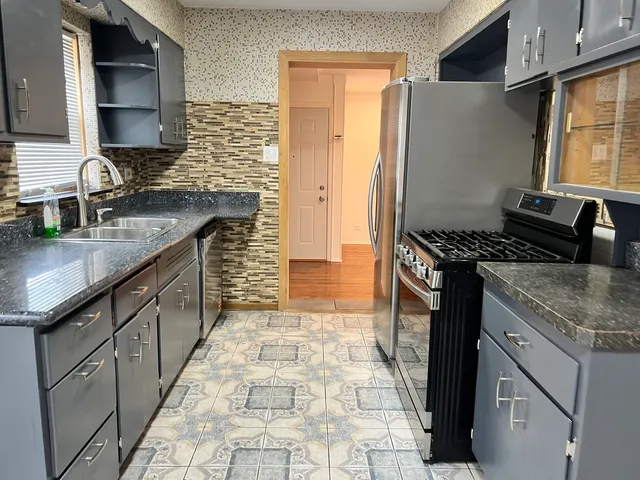 a kitchen with granite countertop a sink stove and cabinets