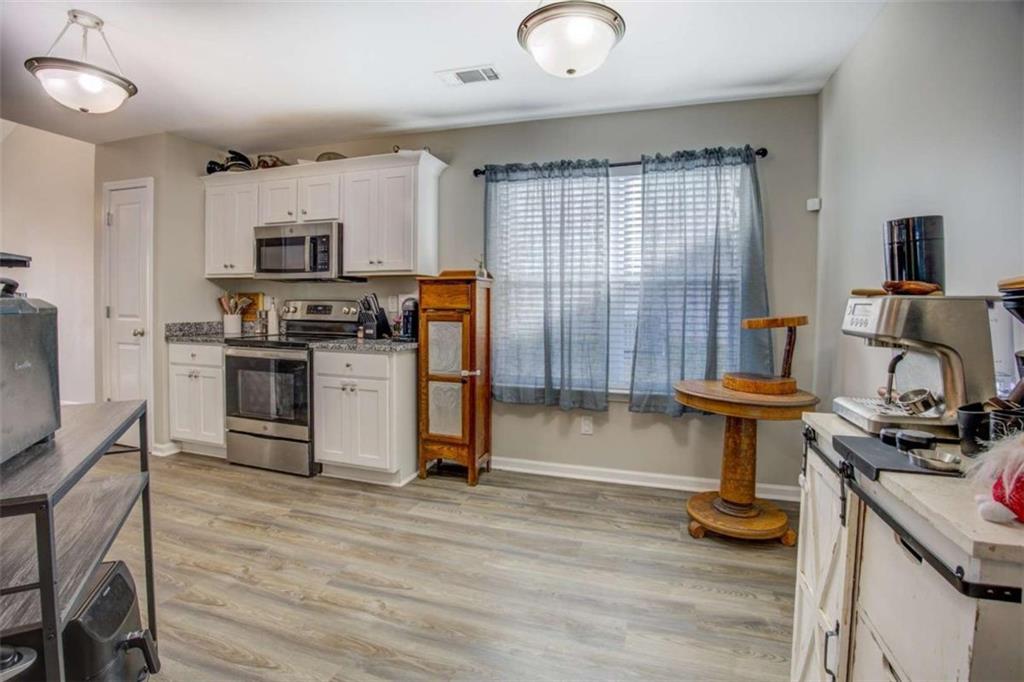 160 Savannah Way Milner, GA 30257 - Photo 11 of 41 a kitchen with stainless steel appliances granite countertop a stove top oven a sink dishwasher a dining table and chairs with wooden floor
