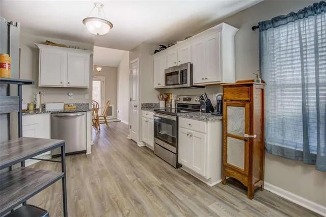 a kitchen with stainless steel appliances white cabinets and wooden floors